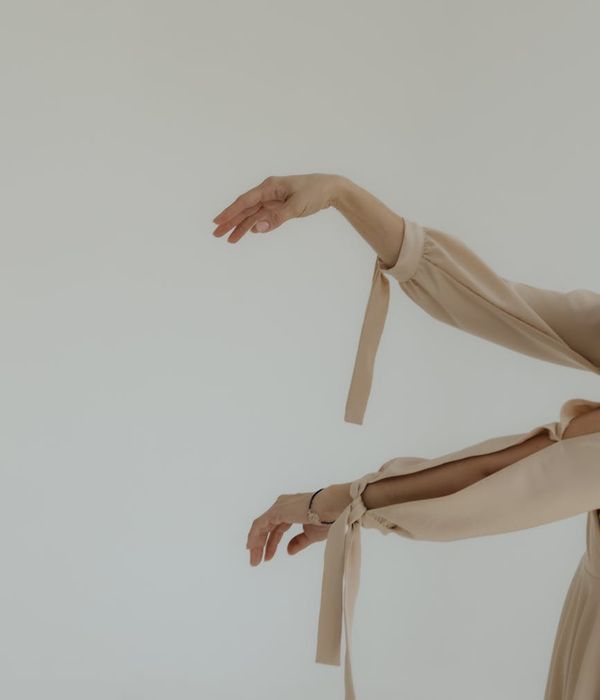 Woman performing a gentle, flowing movement in a bright, minimalist room.